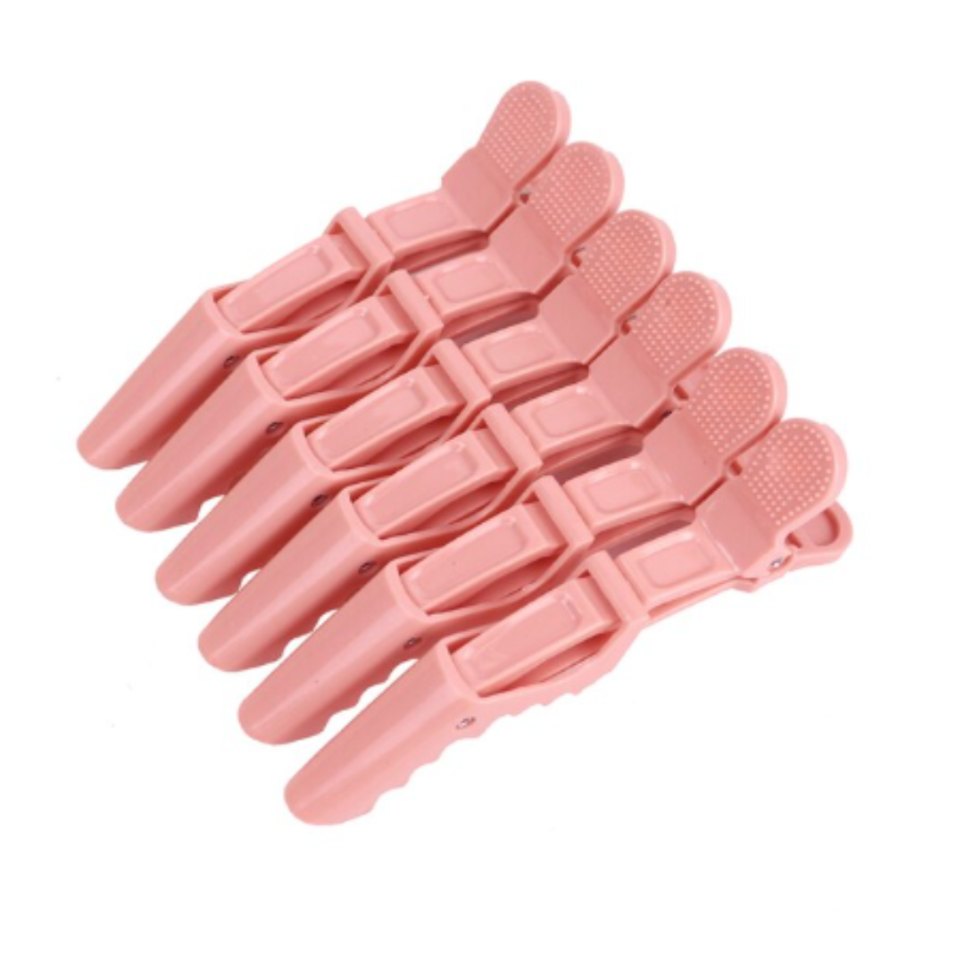 A set of six pink alligator hair clips arranged in a fan-like spread on a white background.